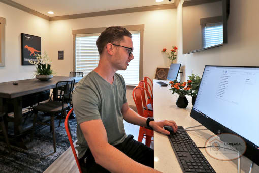 A man sitting at a computer in the business center doing work.