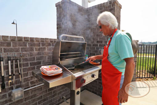 A man in an apron preparing food on a barbecue grill.