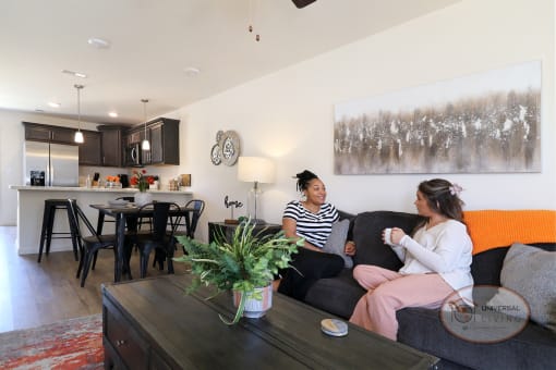 Two women sitting on a couch in a living room in an apartment.