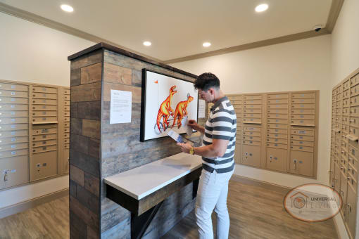 A man standing in front of the table in the mail room, looking through mail.