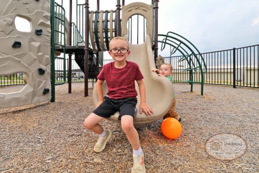 Two children playing on a slide at a playground.