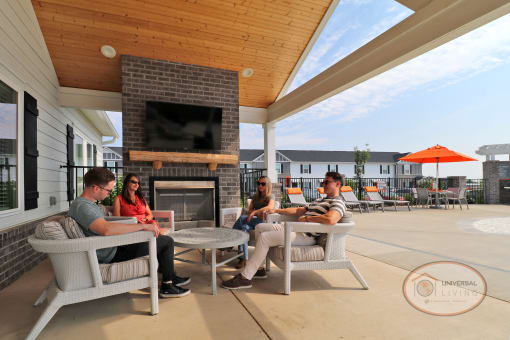 A group of people sit around the poolside lounge, talking.