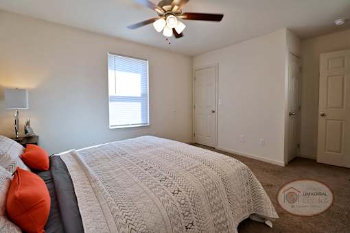 A bedroom with a large bed and a ceiling fan.