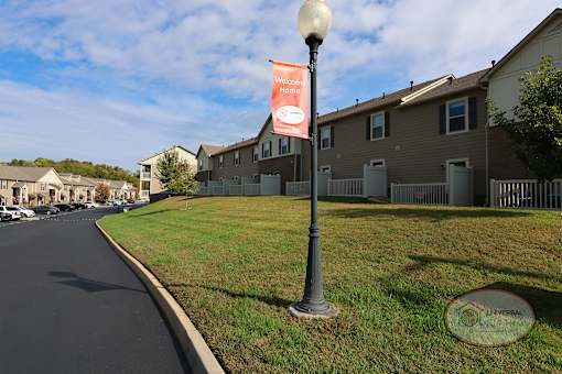 A street lamp with a banner that says "Welcome Home" is in front of apartment buildings.