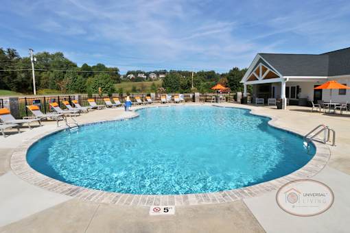A view of the swimming pool from the 5 foot deep end with lounge chairs and the clubhouse in the background.