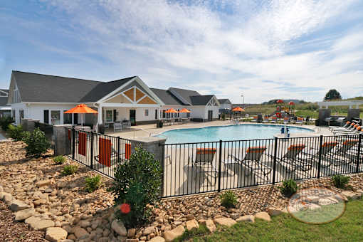 A landscape view of the clubhouse and pool surrounded by fencing.