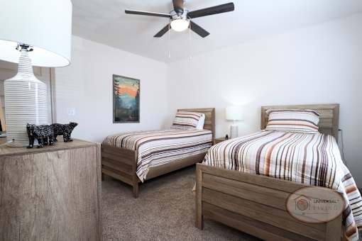 A bedroom with two twin beds, a ceiling fan, and carpet.