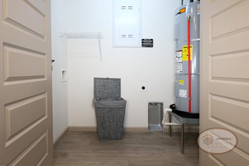 A laundry room with washer and dryer hookups, water heater, and clothes bin.