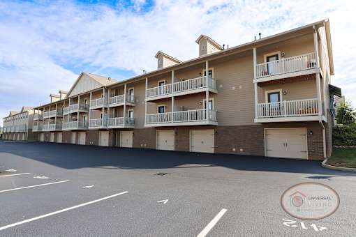 A row of apartment buildings with a parking lot in front.
