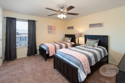 A bedroom with two twin beds, carpet, and a ceiling fan.