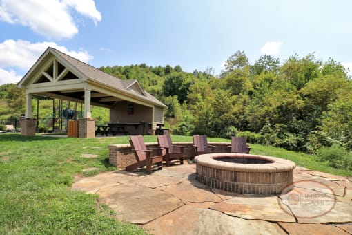 A fire pit with lounge chairs and a covered picnic area in the background.