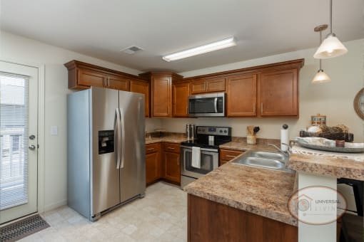 A kitchen with stainless steel appliances, dark cabinets, white walls and tile flooring.