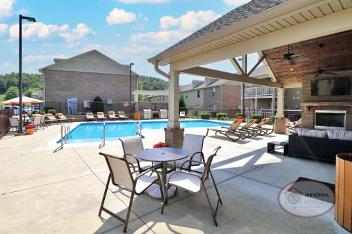 The poolside lounge with flat screen TV, lounge seating, and a table with chairs.