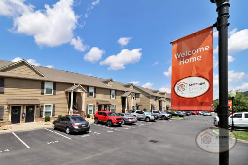 An orange welcome home sign in front of a row of apartment buildings.