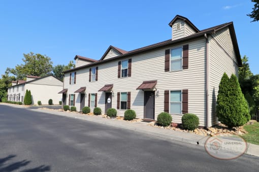 A row of white apartment buildings with brown door and shutters.