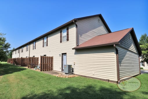 The rear of an apartment home with attached garage and patios.