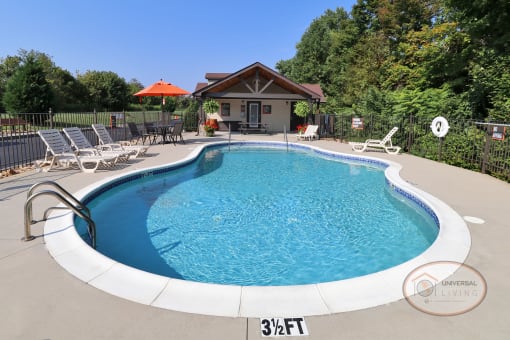 A pool with large sundeck, complete with lounge chairs and tables with umbrellas.