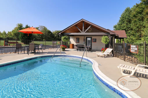 A pool with large sundeck, complete with lounge chairs and tables with umbrellas.