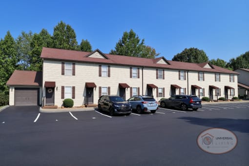 A row of white apartment homes with brown door and shutters and an attached garage on both ends.