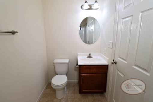 A bathroom with a toilet, sink and mirror.