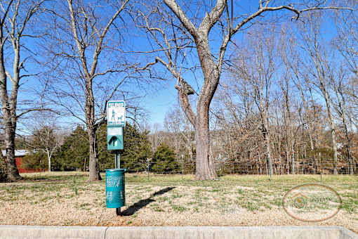 A pet waste pick-up station on a grassy flat area.