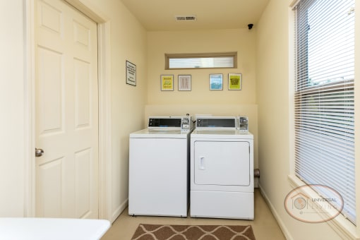 a laundry room with two washer and dryers and a window and a door