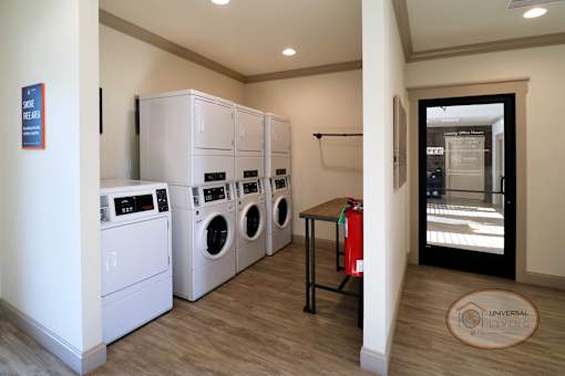 a laundry room with washer and dryers and a door to a hall way