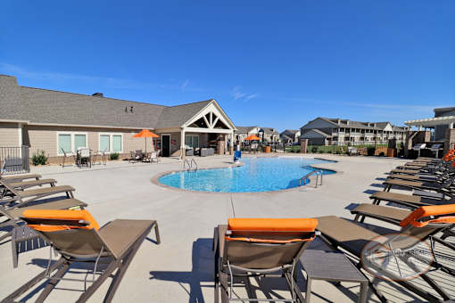 a large pool with chairs around it and a building in the background