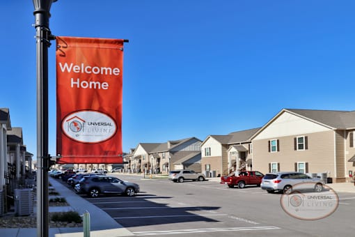 a welcome home sign hangs over a parking lot in front of a row of houses