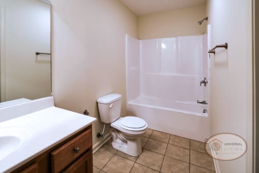 A bathroom with a toilet and a tub and a sink with tile flooring.