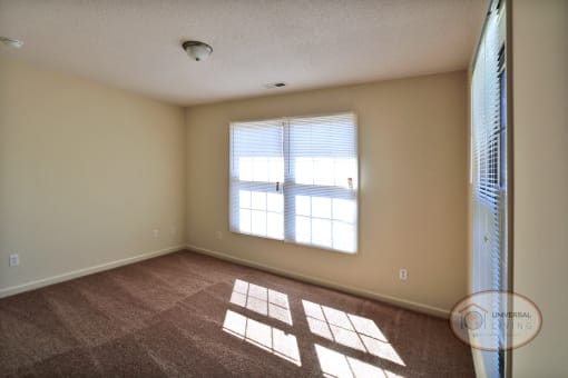 An empty bedroom with carpet and large windows.