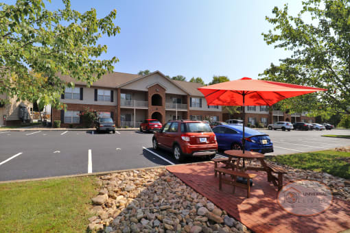 A photo of the property, centered on a picnic table with an umbrella. in front of an apartment building
