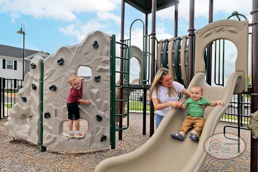 A mother and two children playing on a slide on a playground.