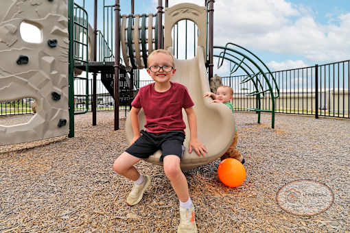 Two young children play on a slide at the playground.