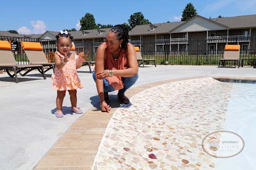 A woman and a little girl are playing by a pool.