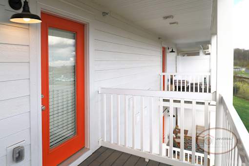 A balcony with an orange glass door.