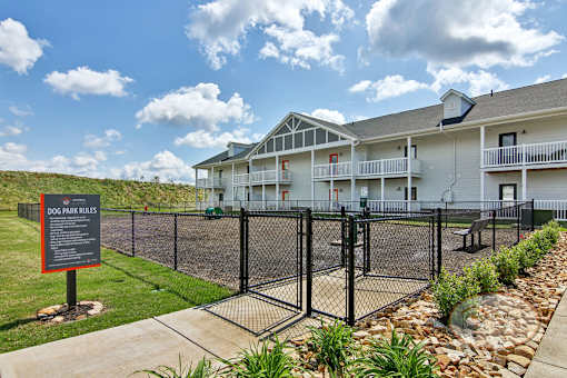 A fenced in dog park with obstacles for pets, and a bench.