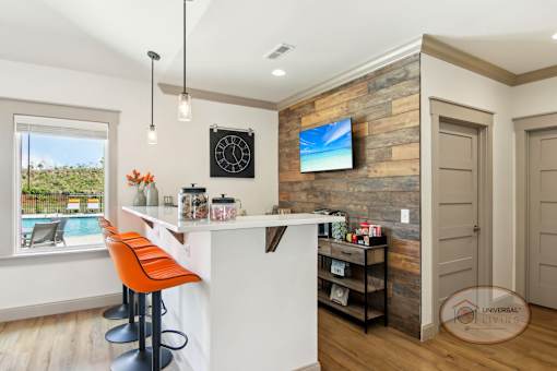 A coffee bar with bar seating and a flat screen TV on a stone accent wall.