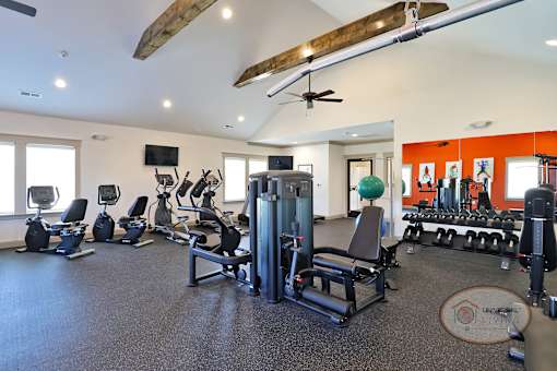 A fitness center with weight training and cardio equipment in front of a wall of mirrors.