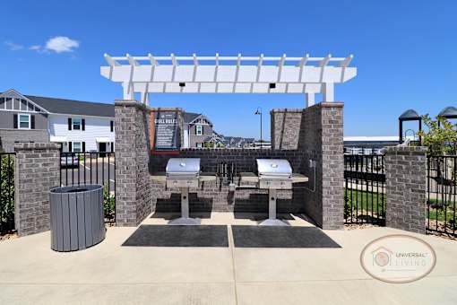 Two stainless steel grills sit next to the pool, complete with trash can and grilling tools.