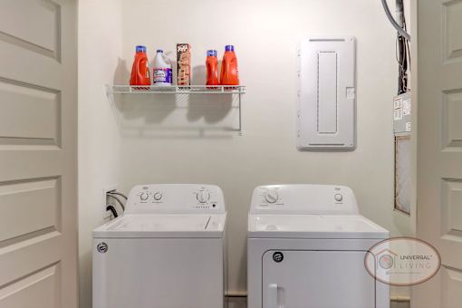 A laundry room with a washer and dryer and a shelf with bottles of detergent.