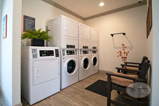 The community laundry center with a washers and dryers, a rack, and seating.