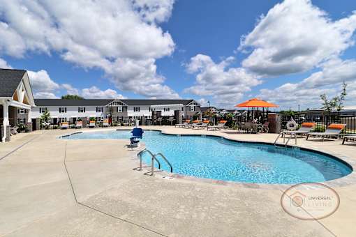 A swimming pool with a blue sky and rows of white and gray apartments in the background.