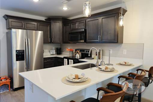 A modern kitchen with a white island and dark brown cabinets.