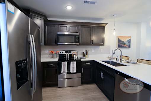 A kitchen with a stainless steel refrigerator and black cabinets.