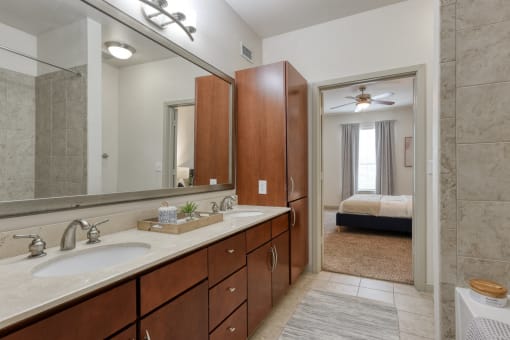 a bathroom with a sink and a mirror and a bedroom with a bed