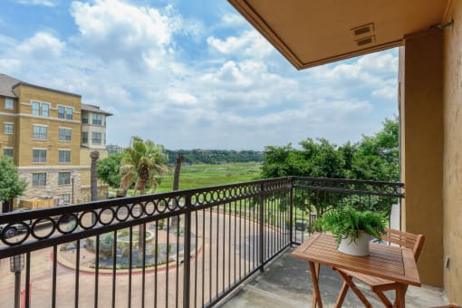 a balcony with a table and chairs and a view of a garden