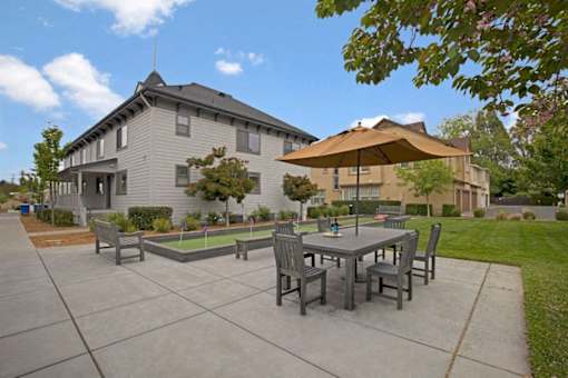 A patio with a table and chairs is in front of a house.