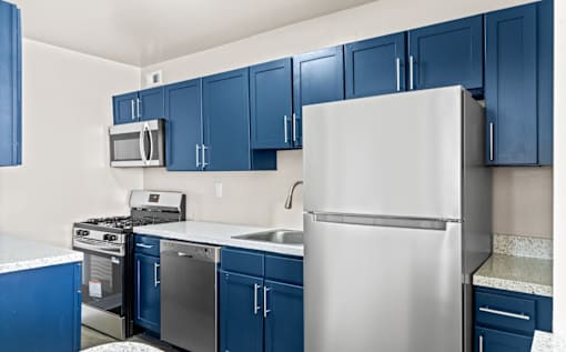 Modern kitchen with blue cabinets and stainless appliances at Dominion Towers Apartments, Virginia, 22204