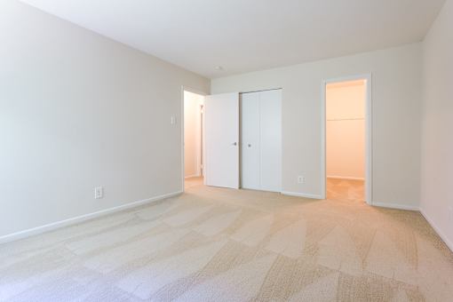 A room with a carpeted floor and two white doors at Potomac Ridge Apartments, Woodbridge, 22191